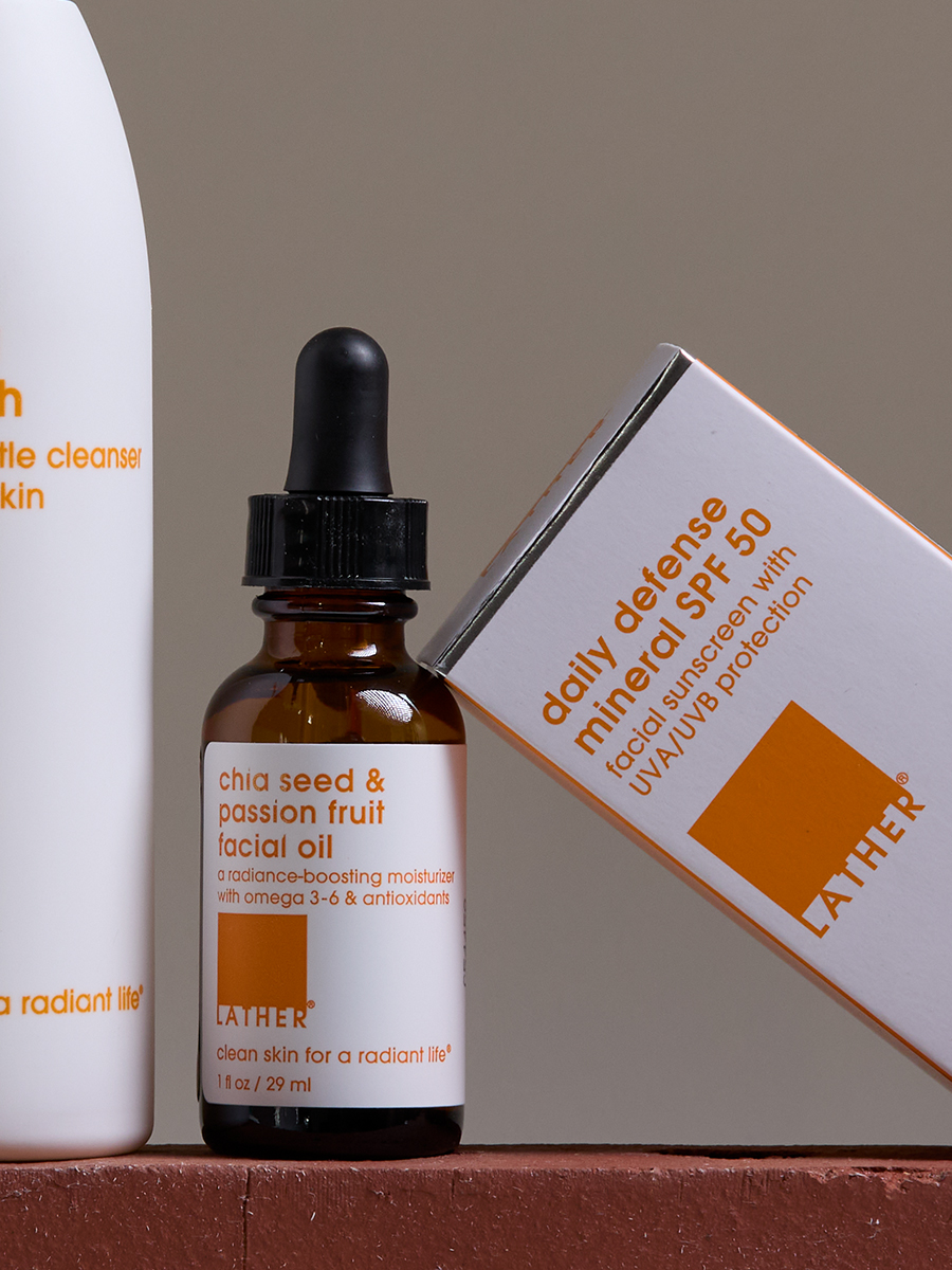 Lather chia seed & passion fruit facial oil and daily defense mineral SPF 50 box leaning together on a terracotta ledge.