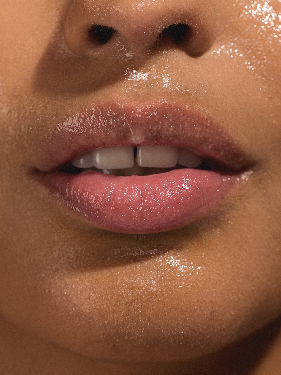 Extreme close-up of a model's glossy lips and nose in bright sunlight.