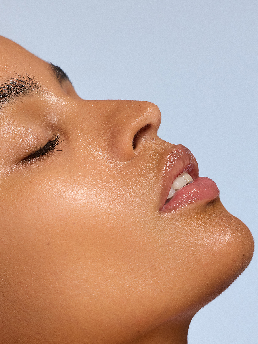 Profile close-up of a model's face in soft light, lips slightly parted, eyes closed.