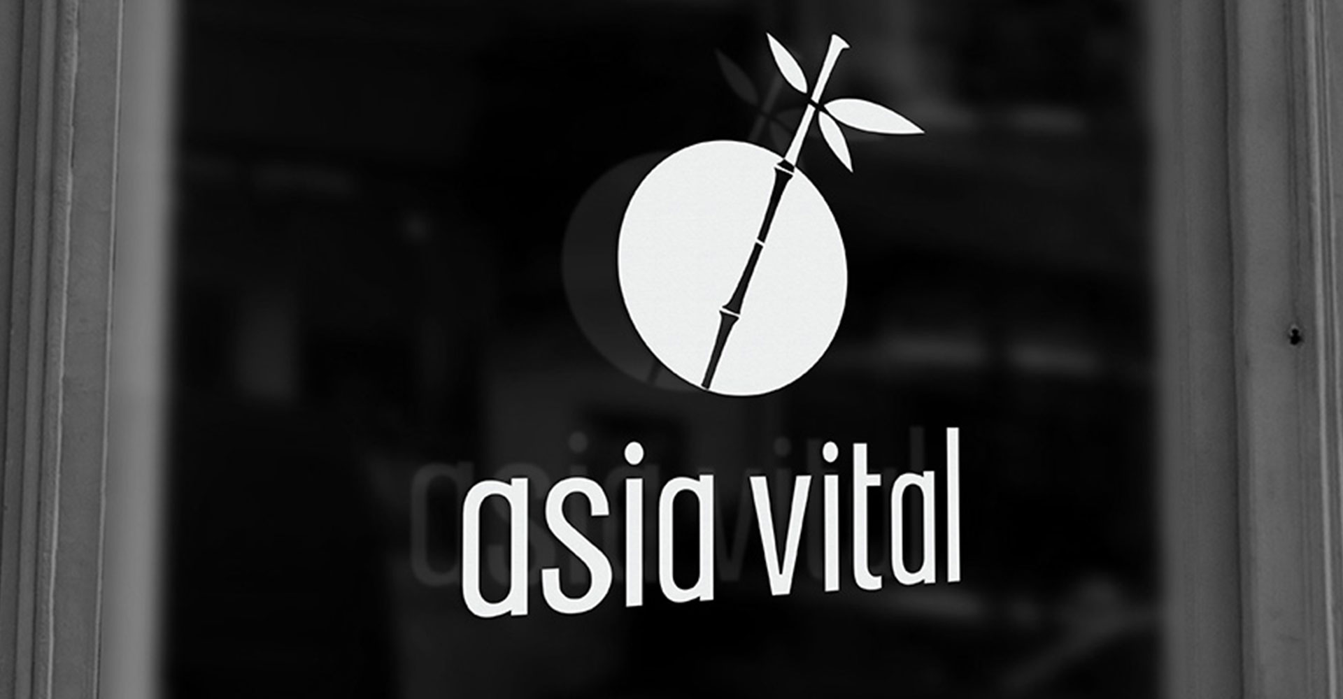 Asia Vital logo — a white circular mark with a bamboo stalk and leaves crossing through it — etched onto a dark storefront window above the wordmark 'asia vital'.