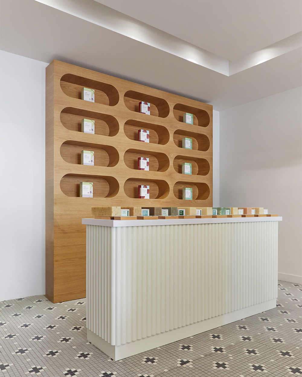 Interior of the Lather Pasadena store, with product niches carved into a wood display wall above a ribbed checkout counter.